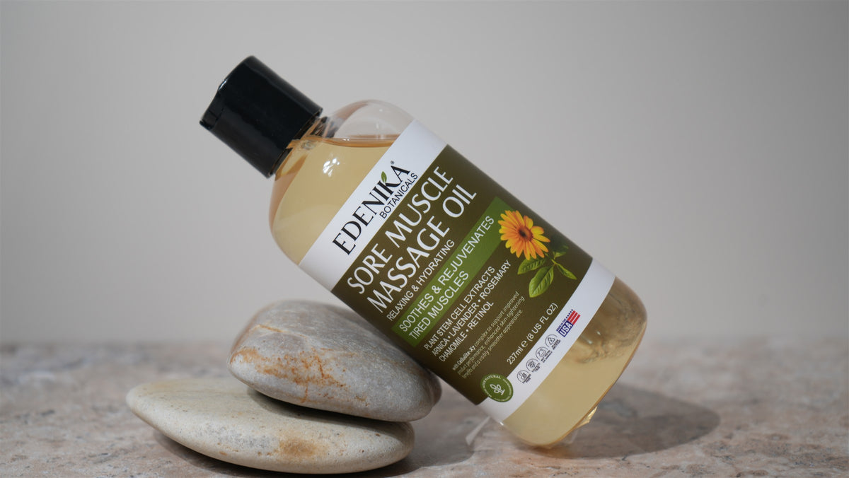 Edenika Sore Muscle Massage Oil resting on smooth spa stones